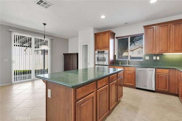 kitchen featuring pendant lighting, a center island, stainless steel appliances, backsplash, and light tile patterned flooring