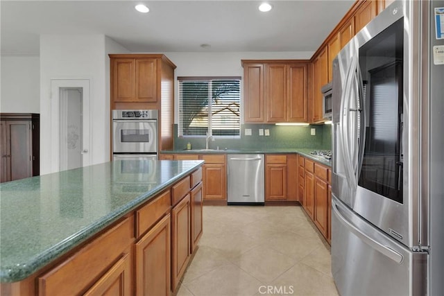 kitchen with appliances with stainless steel finishes, light tile patterned floors, decorative backsplash, and sink