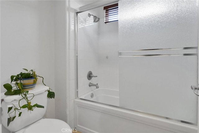 bathroom with toilet and bath / shower combo with glass door