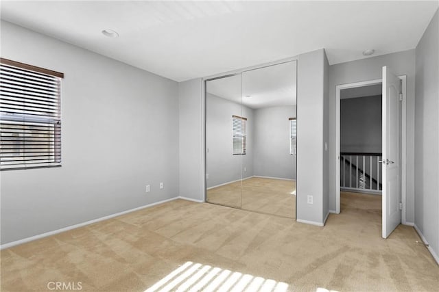 unfurnished bedroom featuring a closet and light colored carpet