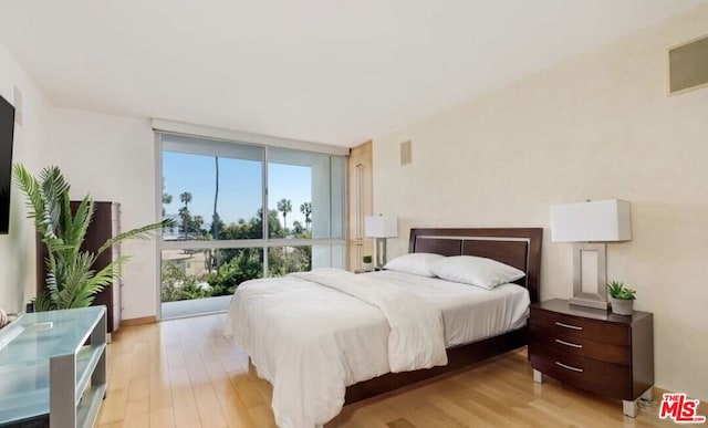 bedroom with floor to ceiling windows and light wood-type flooring