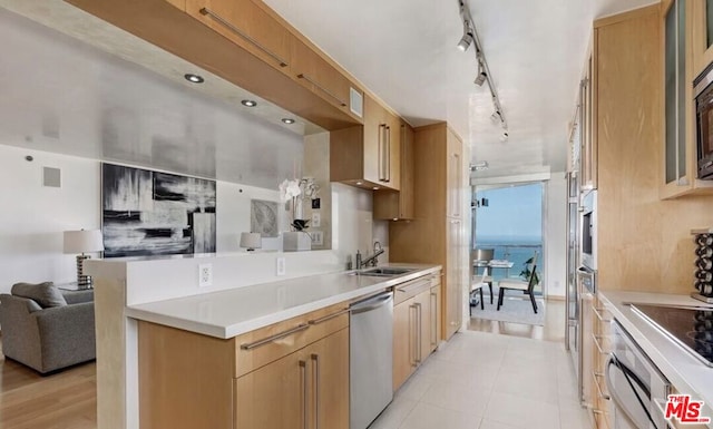 kitchen with stainless steel appliances, light brown cabinetry, light tile patterned floors, and sink