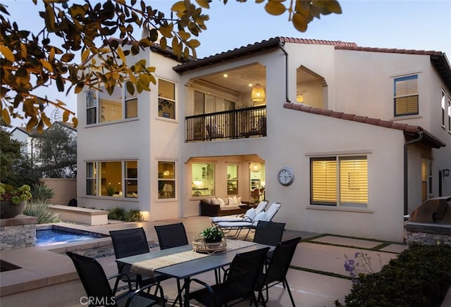 rear view of property featuring an outdoor hangout area, a balcony, a patio, and a hot tub