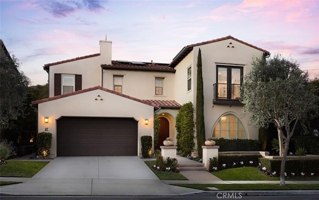 mediterranean / spanish-style house with solar panels, a balcony, and a garage