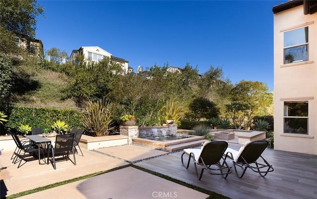 view of patio featuring pool water feature, a fire pit, and a jacuzzi