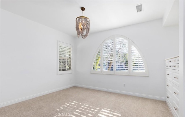 unfurnished room with an inviting chandelier and light colored carpet