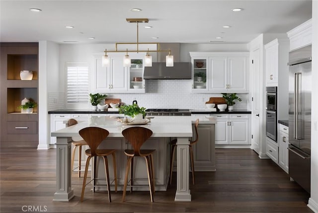 kitchen with appliances with stainless steel finishes, hanging light fixtures, a breakfast bar, a kitchen island, and white cabinets