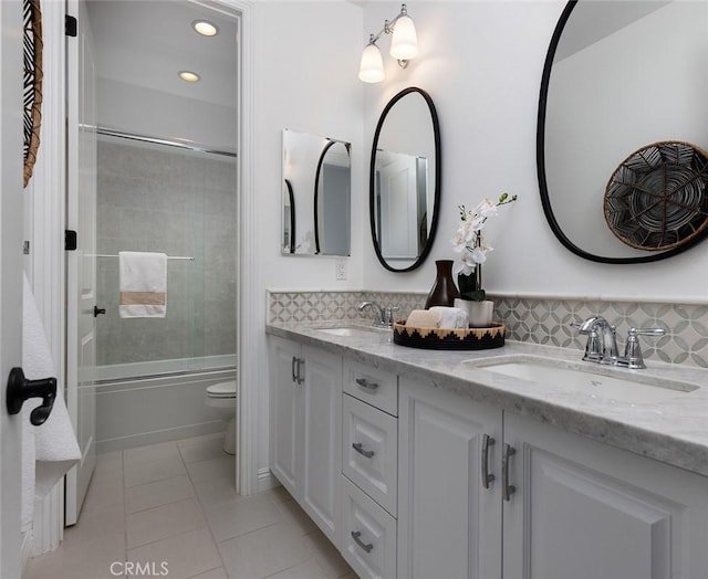 full bathroom featuring tile patterned flooring, tiled shower / bath combo, toilet, vanity, and decorative backsplash