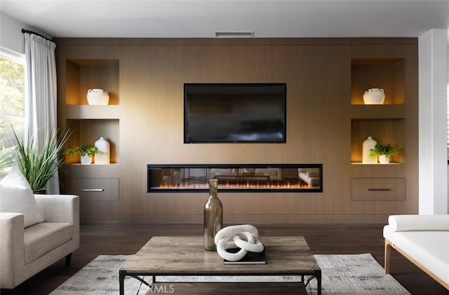 living room with built in shelves and dark hardwood / wood-style floors