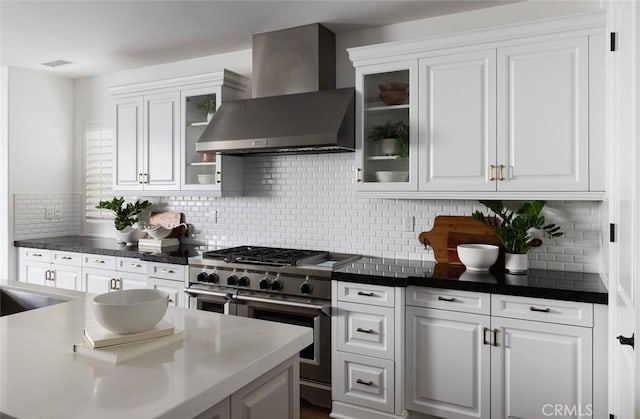 kitchen featuring sink, white cabinetry, wall chimney exhaust hood, decorative backsplash, and double oven range