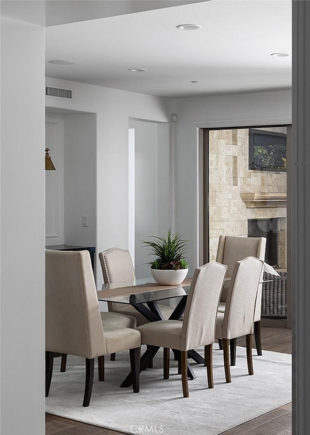 dining room with wood-type flooring and a fireplace