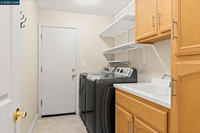 washroom with sink, light tile patterned flooring, separate washer and dryer, and cabinets