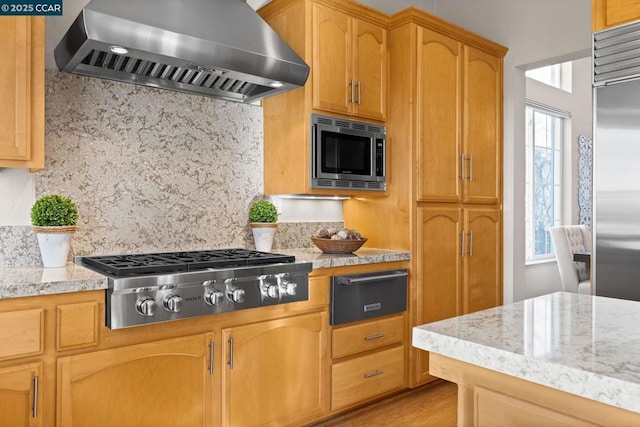 kitchen featuring built in appliances, extractor fan, backsplash, and plenty of natural light