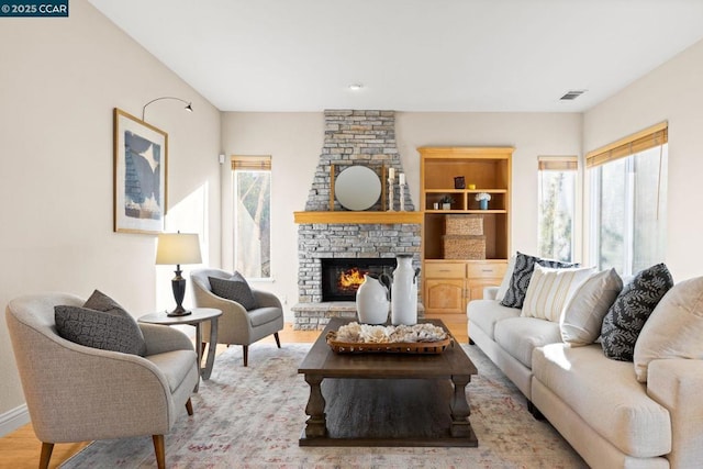 living room with light wood-type flooring and a stone fireplace