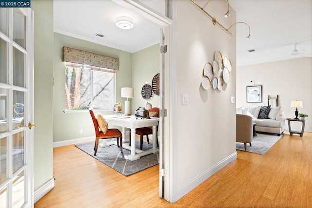 hallway with ornamental molding and light hardwood / wood-style flooring