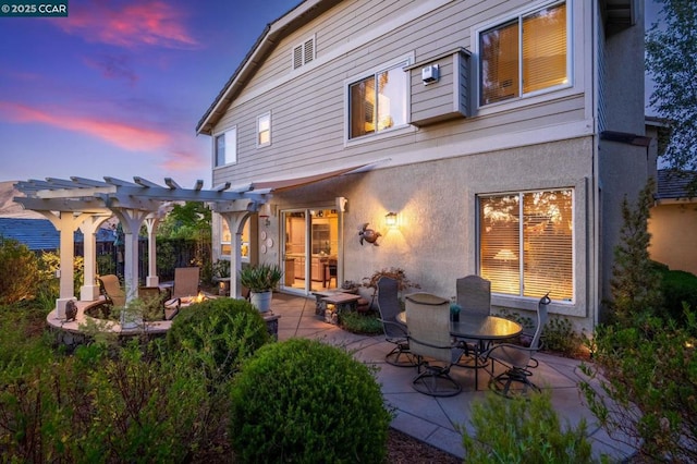 back house at dusk with a pergola and a patio