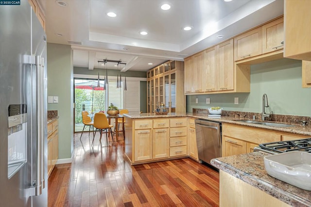 kitchen with kitchen peninsula, appliances with stainless steel finishes, hanging light fixtures, and light brown cabinets