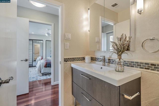 bathroom featuring ceiling fan, tile walls, vanity, and hardwood / wood-style flooring