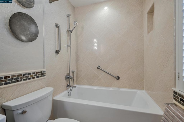 bathroom with toilet, tiled shower / bath combo, and tile walls