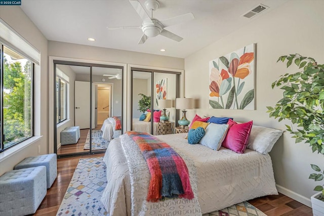 bedroom featuring dark wood-type flooring, two closets, and ceiling fan