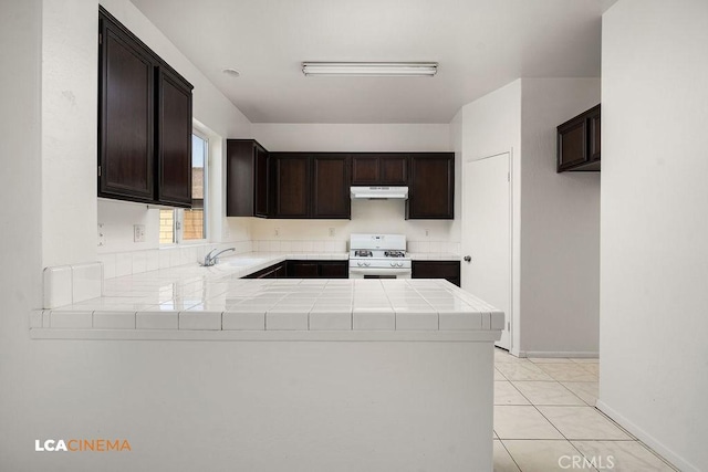 kitchen with white gas range oven, dark brown cabinets, and kitchen peninsula