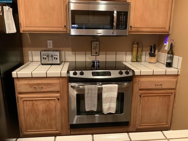 kitchen with appliances with stainless steel finishes and tile counters