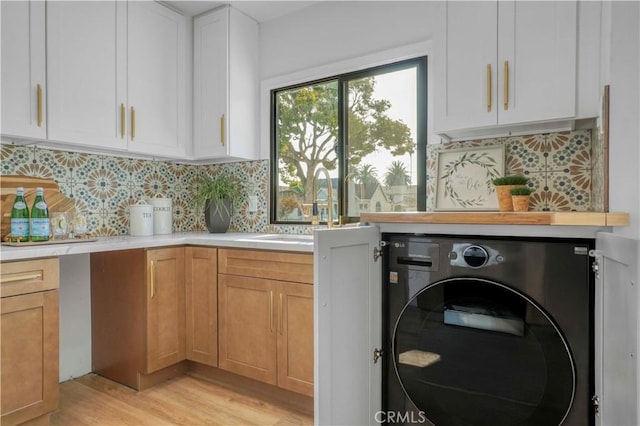 laundry room featuring light hardwood / wood-style floors, cabinets, washer / dryer, and sink