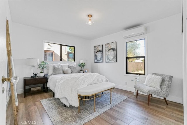 bedroom with wood-type flooring and an AC wall unit