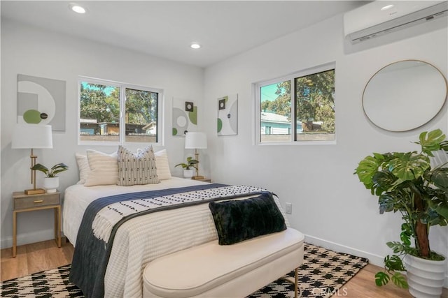 bedroom with a wall mounted air conditioner and hardwood / wood-style flooring