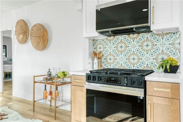 kitchen featuring gas range oven, light hardwood / wood-style flooring, light brown cabinetry, tasteful backsplash, and white cabinets