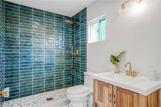 bathroom featuring toilet, vanity, and tiled shower