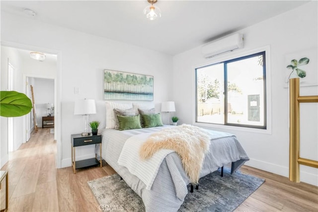 bedroom with light hardwood / wood-style floors and a wall mounted AC