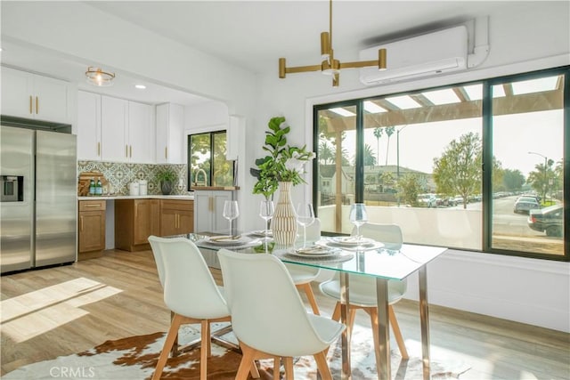 dining area featuring light hardwood / wood-style flooring and an AC wall unit