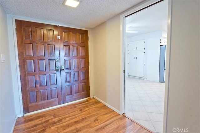 foyer entrance with a textured ceiling and light hardwood / wood-style floors