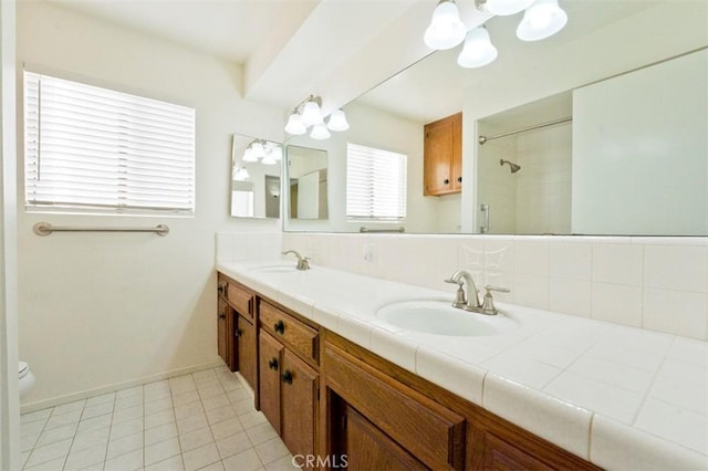 bathroom with toilet, tile patterned flooring, a tile shower, and vanity