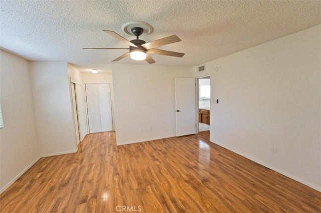 unfurnished room featuring ceiling fan, light wood-type flooring, and a textured ceiling