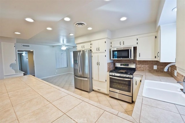 kitchen featuring white cabinetry, stainless steel appliances, tile counters, backsplash, and sink