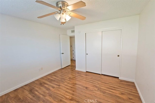 unfurnished bedroom featuring ceiling fan, wood-type flooring, a closet, and a textured ceiling