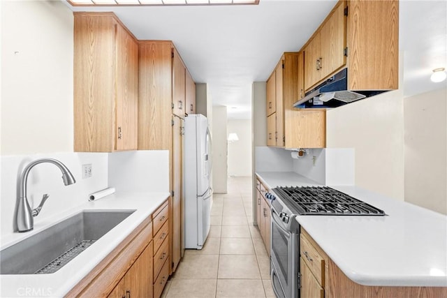 kitchen featuring sink, light tile patterned floors, gas range, and white fridge