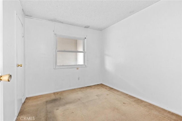 spare room featuring a textured ceiling and light carpet