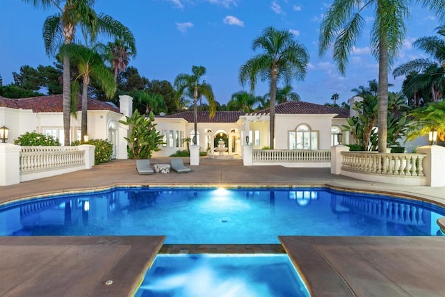 pool at dusk featuring a patio