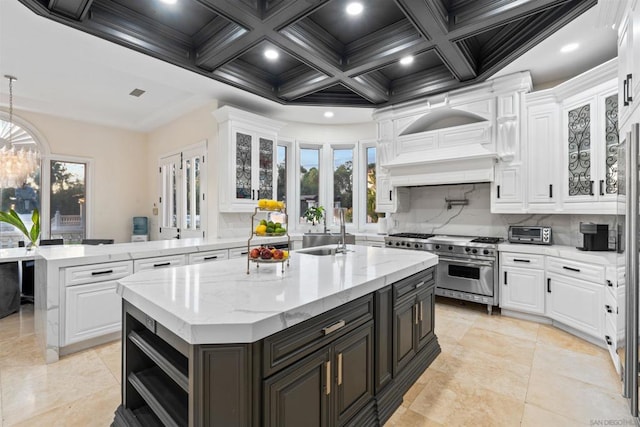 kitchen featuring sink, white cabinetry, a kitchen island with sink, and range with two ovens