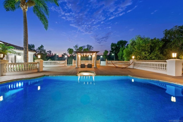 pool at dusk with a pergola and a patio area