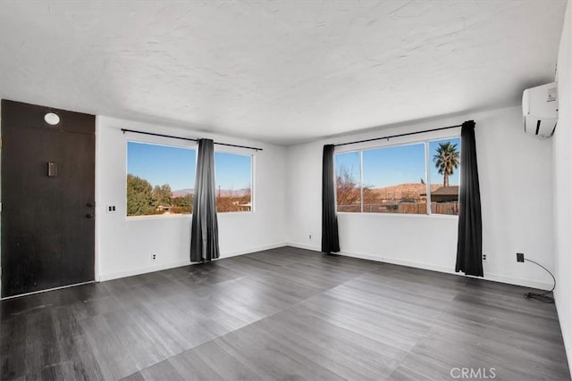 empty room featuring a wall mounted AC and dark hardwood / wood-style floors