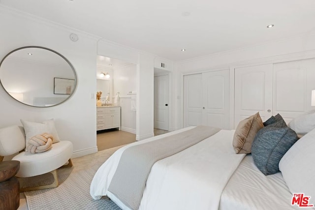 bedroom featuring ensuite bath, crown molding, and multiple closets