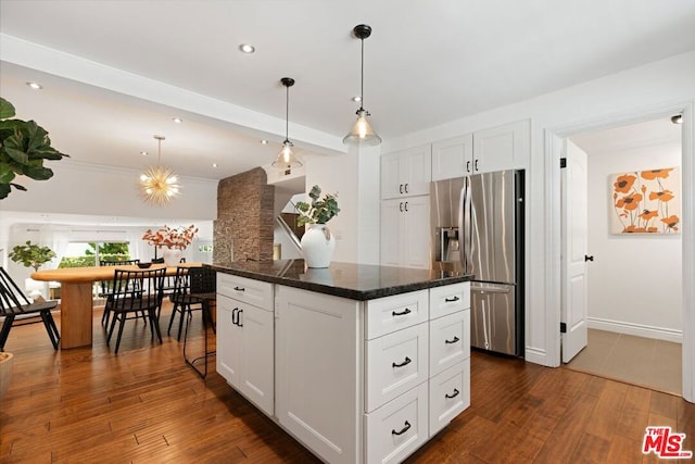 kitchen featuring white cabinets, stainless steel fridge with ice dispenser, dark stone countertops, and hanging light fixtures