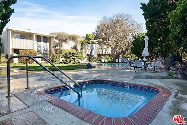 view of pool featuring a community hot tub, a patio area, and a grill