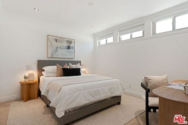 bedroom with ornamental molding and light colored carpet