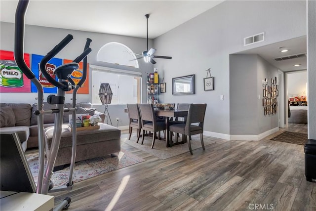 dining space featuring ceiling fan, a towering ceiling, and wood-type flooring