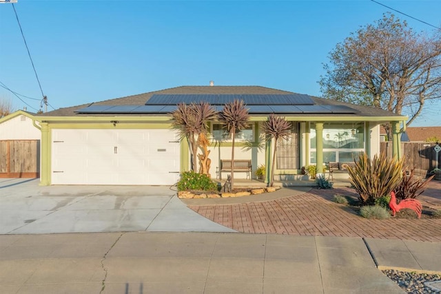 view of front facade with a garage, covered porch, and solar panels